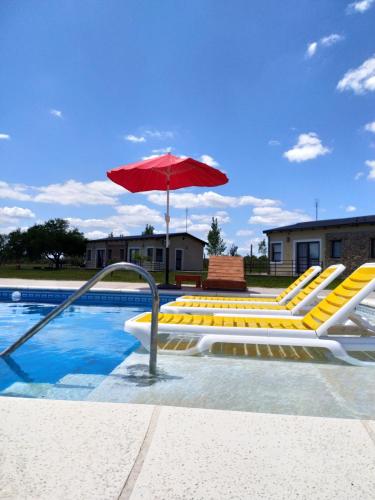 乌拉圭河畔康塞普西翁Ndori Bungalows的游泳池设有黄色躺椅和遮阳伞