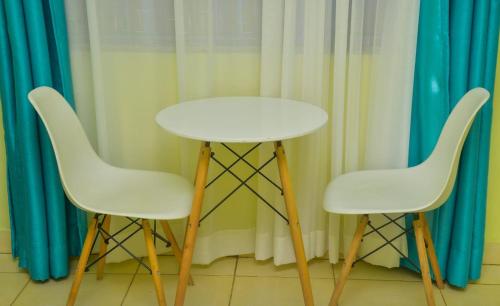 ChukaThe O,S Homestay的窗帘前设有两把白色椅子和一张白色桌子