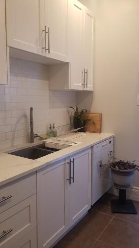 渥太华Tina's gem的厨房配有白色橱柜和水槽