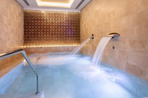 马德里阿托查加泰罗尼亚酒店的浴室内设有带喷泉的热水浴池