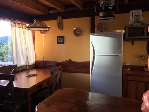 拉安戈斯图拉镇Cabañas Ruca Nahuel的带冰箱和桌子的厨房以及用餐室