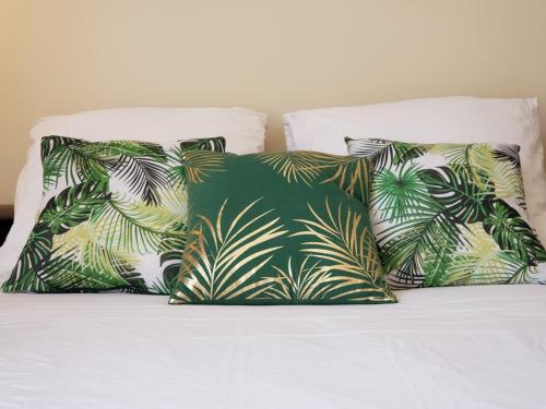 鲁昂Appart Rouen Centre的一张带三个枕头的床,棕榈叶