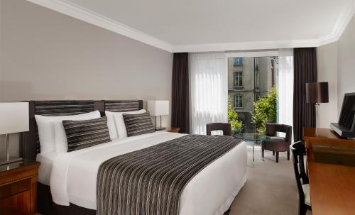日内瓦Hotel President Wilson, a Luxury Collection Hotel, Geneva的一间卧室配有一张床、一张书桌和一台电视