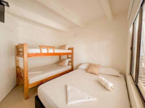 圣玛尔塔Hotel Tamara House的小型客房设有两张双层床和窗户。