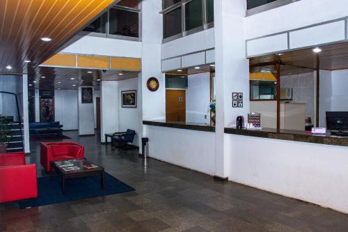 马瑙斯Plaza Prestige Hotel Manaus的大堂设有柜台和红色椅子