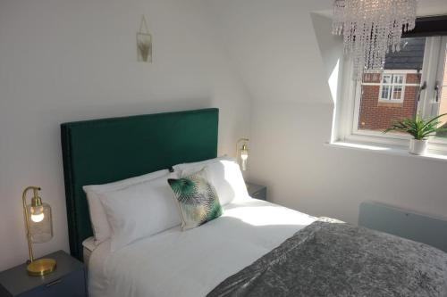 切姆Tulip Place的一间卧室配有一张带绿色床头板的床和窗户