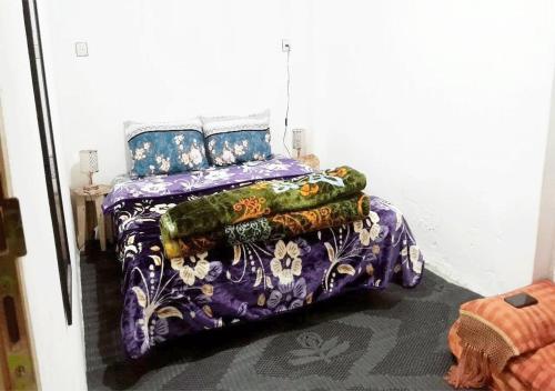 萨菲1A private room in a shared house for surfers的一张带紫色棉被和枕头的床