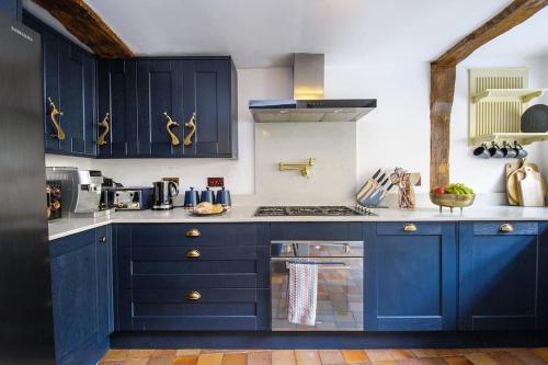 萨弗伦沃尔登Huge & Deluxe 600 Year Old Essex Manor House的厨房配有蓝色橱柜和炉灶。