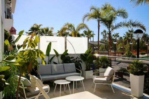 莫特里尔Aguacate Beach Apartamentos Playa Granada的一个带沙发和椅子的庭院,并种植了棕榈树。