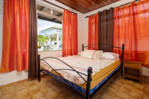 PaeaApetahi Lodge的一间卧室配有床和橙色窗帘的窗户