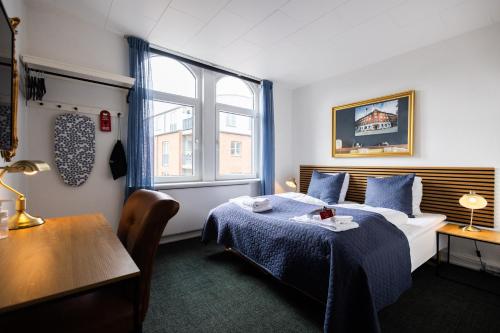 欧登塞Milling Hotel Windsor的客房设有床、桌子和窗户。