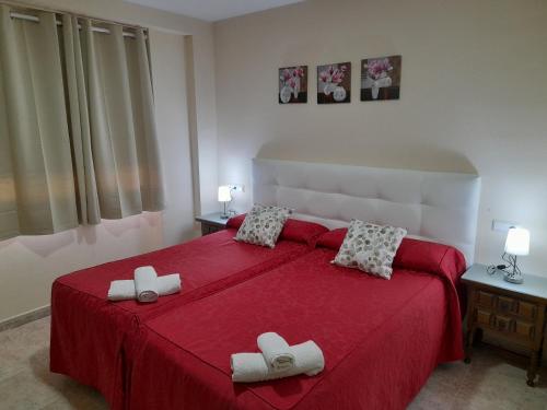瓜达拉哈拉Hostal San Roque的一间卧室配有红色的床和2拖鞋