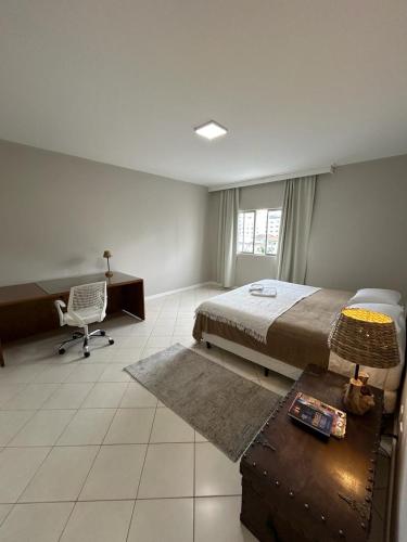 拉热斯Apartamento NOVO no centro/Via Gastronômica的一间卧室配有一张床、一张桌子和一把椅子