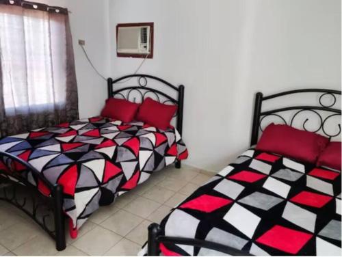 库利亚坎Departamento con servicio de facturación的一间卧室配有两张带红色枕头的床