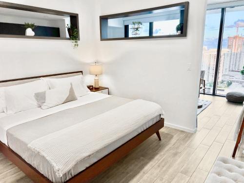 劳德代尔堡Sleek & Stylish Jr. 1-BR Retreat - Las Olas的一间卧室配有一张带白色床单和窗户的床。