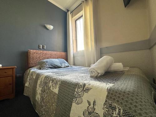 康塞普西翁Hotel Vitali的一间卧室配有一张带毯子的床和窗户