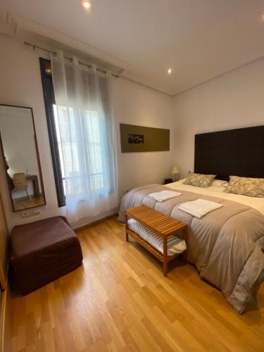 卡塞雷斯Apartamentos Caceres的一间卧室配有两张床、一张长凳和镜子