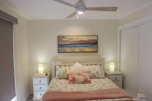 日落大道Palm Breeze at Sunset Strip的一间卧室配有一张带吊扇的床