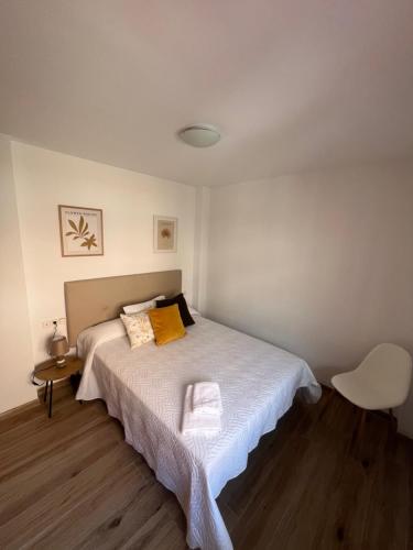 梅利利亚AB Apartamentos的一间卧室配有一张床和一张白色椅子