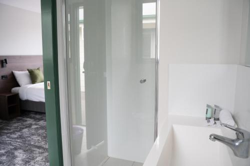 黄金海岸Wallaby Hotel的带淋浴、盥洗盆和浴缸的浴室