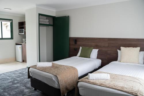 黄金海岸Wallaby Hotel的酒店客房设有两张床和一张桌子。