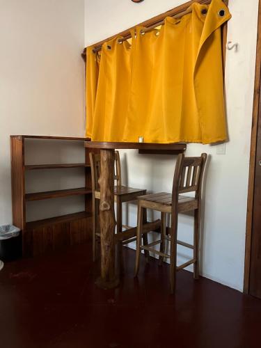 南圣胡安Buena Onda Backpackers的一张带黄色窗帘的桌子和两把椅子