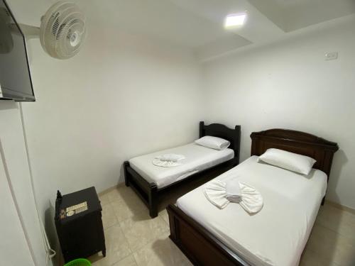 图卢阿Hotel Lina Maria的小型客房配有2张床和风扇。