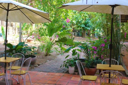 白马市Casa Kep Eco Bed & Breakfast的一个带桌椅和遮阳伞的庭院