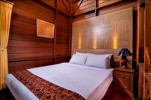 普卡Citra Cikopo Hotel & Family Cottages的卧室配有白色的木墙床