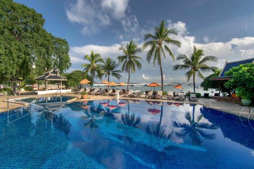 南芭堤雅Siam Bayshore Resort Pattaya的一座棕榈树和海洋的大型游泳池