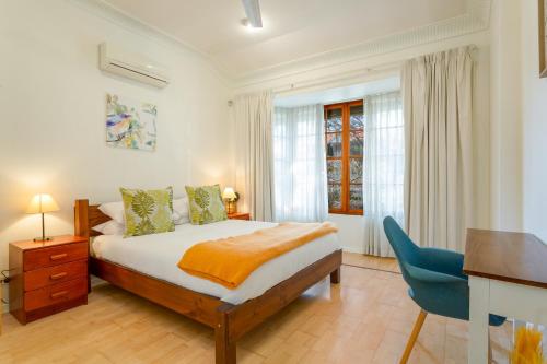 悉尼Spacious 3-Bed Mid Century Home Near CBD的一间卧室配有一张床、一张桌子和一把椅子