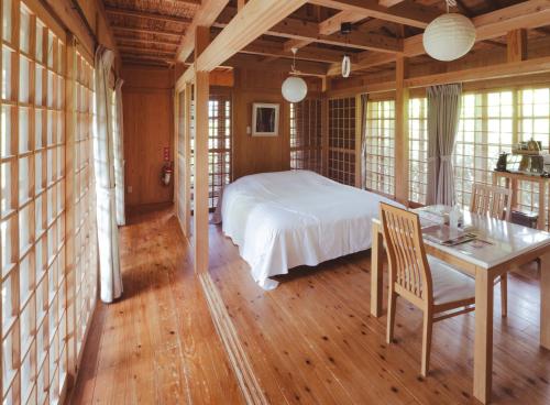 宫古岛かたあきの里的卧室配有一张床和一张桌子及椅子