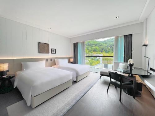 广州广州鸣泉居酒店的酒店客房设有两张床、一张书桌和一个窗户。
