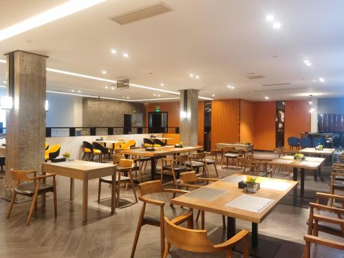 花都柏高酒店(广州北站花城路地铁站店)的配有木桌和椅子的餐厅