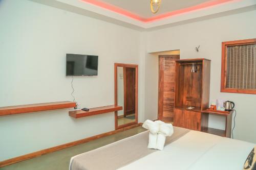 努沃勒埃利耶Mount End Hotel Nuwara Eliya的卧室配有一张床,墙上配有电视。