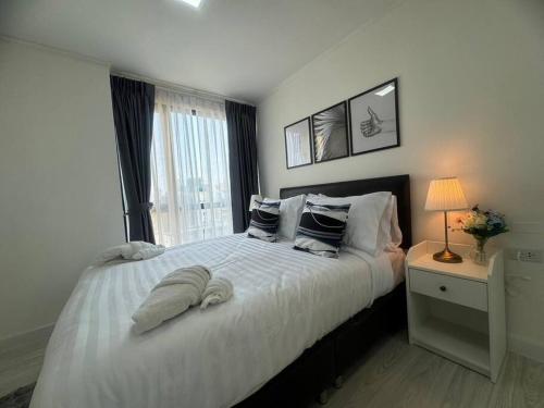 曼那Style Sukumwit Bangna 1的卧室配有带枕头的白色床和窗户。