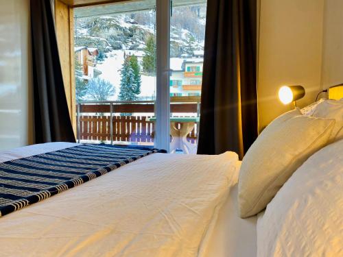 采尔马特Cosy Modern Apartment with balcony and Matterhorn View的一间卧室设有一张床和一个大窗户