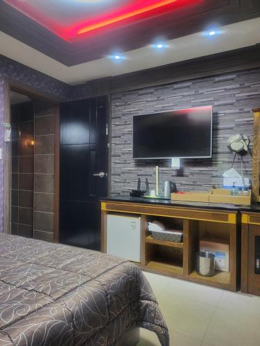 巨济Gohyeon Ace motel的卧室配有一张桌子,砖墙上配有电视