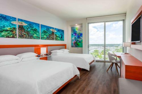 劳德代尔堡Maritime Hotel Fort Lauderdale Airport & Cruiseport的酒店客房设有两张床和大窗户。