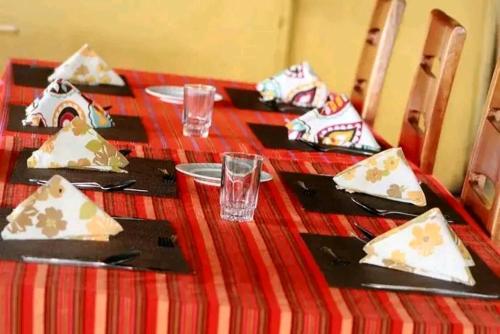Sekenanikubwa mara safari lodge tent camp的一张桌子,上面有红色的桌布,上面有盘子和餐巾