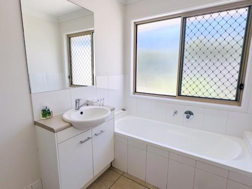 PimpamaSerenity Park Escape at Pimpama的白色的浴室设有水槽、浴缸和窗户。