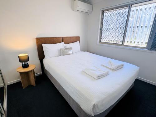 PimpamaSerenity Park Escape at Pimpama的一间卧室配有一张带白色床单的床和一扇窗户。