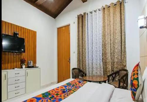 诺伊达HOTEL GLOBAL CORPORATE NOIDA的一间卧室配有一张床、一张桌子和一台电视。