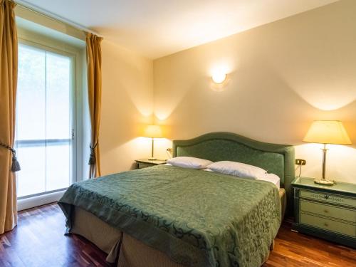 梅纳Residence Villa Greta的一间卧室配有一张带两盏灯和一扇窗户的绿床。