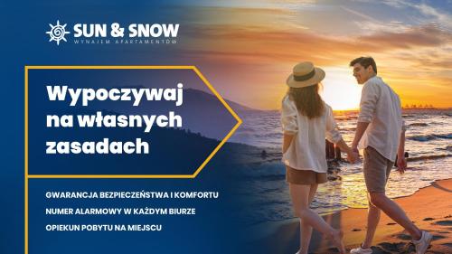 米兹多洛杰Apartamenty Sun & Snow Międzyzdroje Promenada的日落时分在海滩上散步的夫妇
