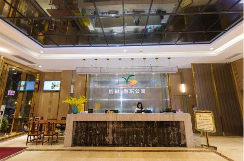 广州Orange Tree International Hotel Zhujiang New Town Huacheng Sqaure Branch - Free Shuttle Bus to Canton Fair Complex During Canton Fair Period的坐在大厅柜台的女人