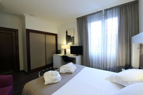 奥维多Gran Hotel España的一间酒店客房,床上配有两个白色枕头
