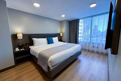 基多La Quinta by Wyndham Quito的一间卧室设有一张大床和一个大窗户