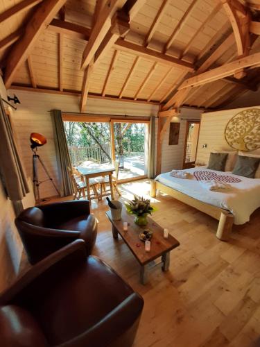 BonlieuCabanes du Hérisson, cabanes perchées de standing avec spa的一间卧室配有一张床、一张沙发和一张桌子