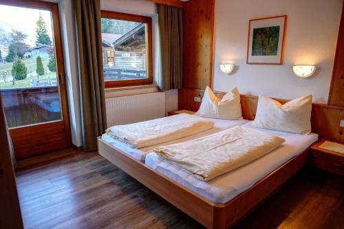 奥法赫虹膜菲林酒店的一间卧室配有一张带白色床单的床和一扇窗户。